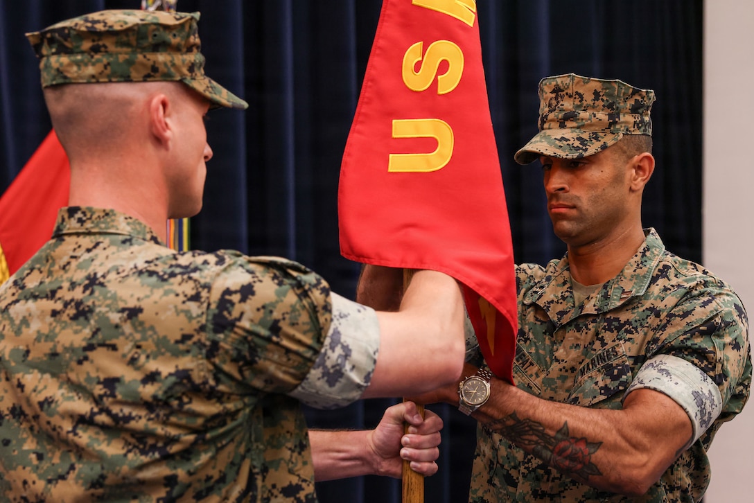 U.S. Marine Corps Capt. Ford Higgins, offgoing company commander, Alpha Company, Marine Barracks Washington, left, presents the guidon to Capt. Vinceint Sweat, incoming company commander, Alpha Company, Marine Barracks Washington during a change of command ceremony at Marine Barracks Washington, D.C., July 2, 2026. Alpha Company is home to several of the Marine Corps' premiere ceremonial units, the official United States Marine Corps Color Guard and the United States Marine Corps Silent Drill Platoon, with two additional platoons of infantry Marines. This transition of leadership represents Alpha Company's continued commitment to the highest standards of the "Oldest Post of the Corps." (U.S. Marine Corps photo by Cpl. Christopher Prelle)