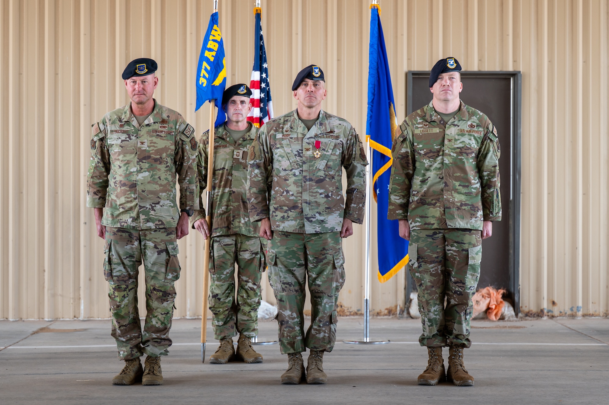Col. Justin D. Secrest, 377th Air Base Wing and installation commander, left, Col. Matthew P. Foisy, outgoing 377th Security Forces Group commander, center, and Col. Alexander R. Liggett, incoming 377th SFG commander, right, stand at attention during the 377th SFG change of command ceremony at Kirtland Air Force Base, New Mexico, July 16, 2026. Secrest presided over the ceremony where Foisy relinquished command of the group to Liggett. (U.S. Air Force photo by Senior Airman Donnell Schroeter)