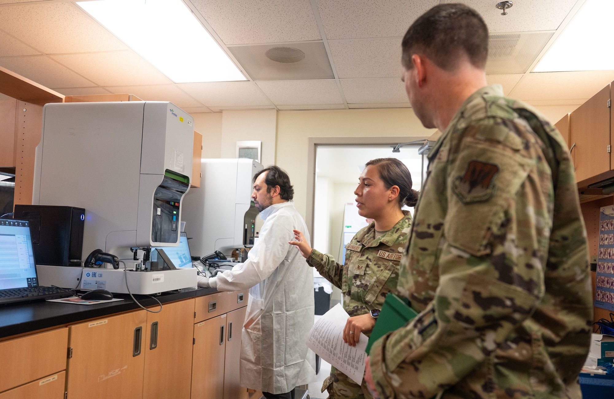 US. Air Force Staff Sgt. Camille Granados, 355th Health Care Operations Squadron chemistry noncommissioned officer in charge, briefs Col. Kyle Porter, 355th Wing deputy commander, in the medical laboratory during an immersion tour at Davis-Monthan Air Force Base, Arizona, July 15, 2026. The laboratory supports warfighter readiness by providing diagnostic testing and medical laboratory services for Airmen and other Department of War beneficiaries. (U.S. Air Force photo by Airman 1st Class Jaden Kidd)