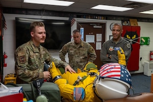 An Airman shows a high altitude flight suit to a commander.
