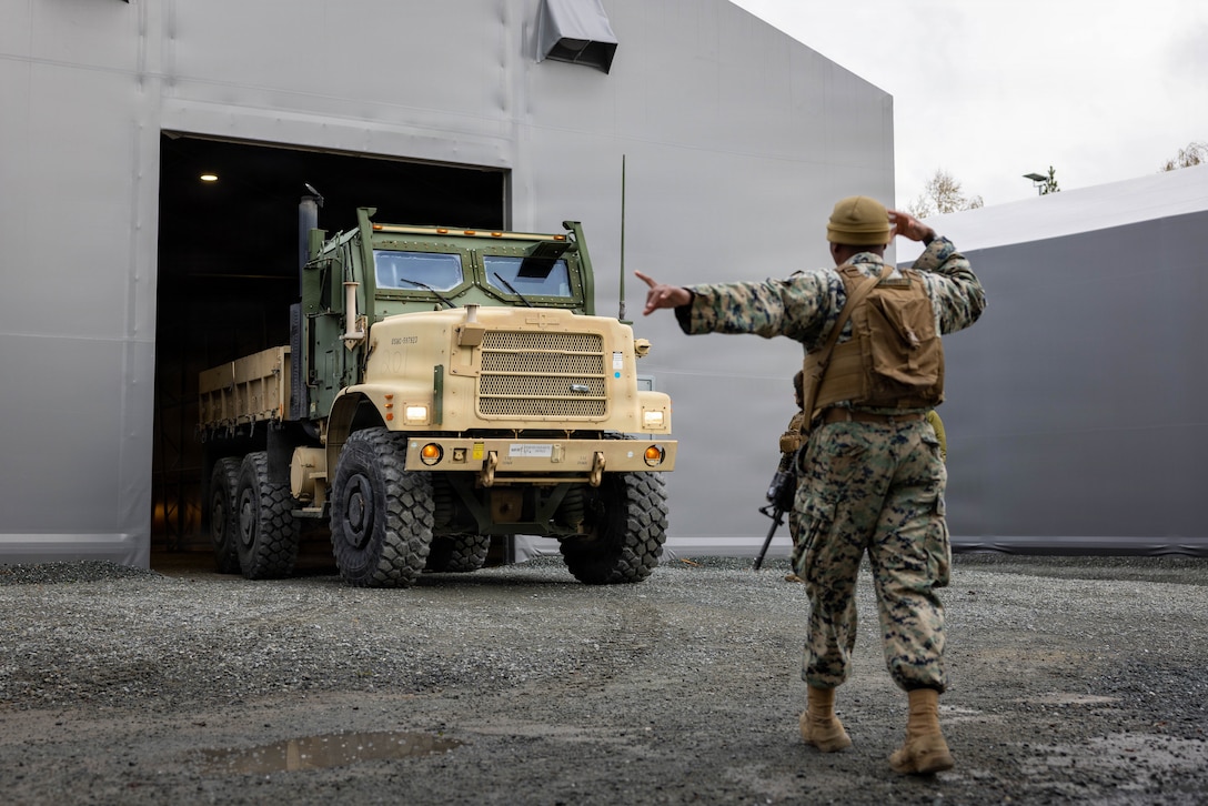U.S. Marine Corps Cpl. Nathanael Olivert, a motor vehicle operator with Combat Logistics Battalion 24, Combat Logistics Regiment 27, 2nd Marine Logistics Group, ground guides a medium tactical vehicle replacement in Værnes, Norway, April 25, 2026. Olivert guided the vehicle prior to a long-range convoy during exercise Aurora 26. U.S. Marines and Sailors with 2nd MLG are participating in exercise Aurora as part of the larger U.S. Army-led Sword 26 series of linked multinational exercises, which directly supports NATO's Eastern Flank Deterrence Initiative concept, validates defense plans, builds a unified lethal force, and strengthens deterrence. Olivert is a native of Florida. (U.S. Marine Corps photo by Lance Cpl. Brady Hathaway)