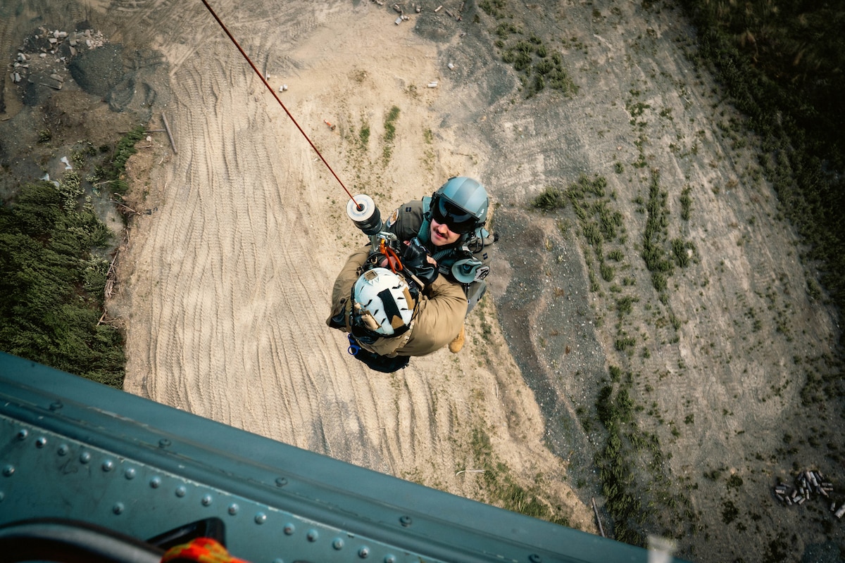 Master Sgt. Daniel Stikeleather, a 212th Rescue Squadron pararescueman, and a simulated casualty are hoisted into an HH-60W Jolly Green II during the Arctic Thunder Open House 26 full-scale exercise at Joint Base Elmendorf-Richardson, Alaska, June 17, 2026. The exercise simulated the recovery of a pilot following an aircraft incident. (U.S. Air Force photo by Airman 1st Class Keola Vischi)