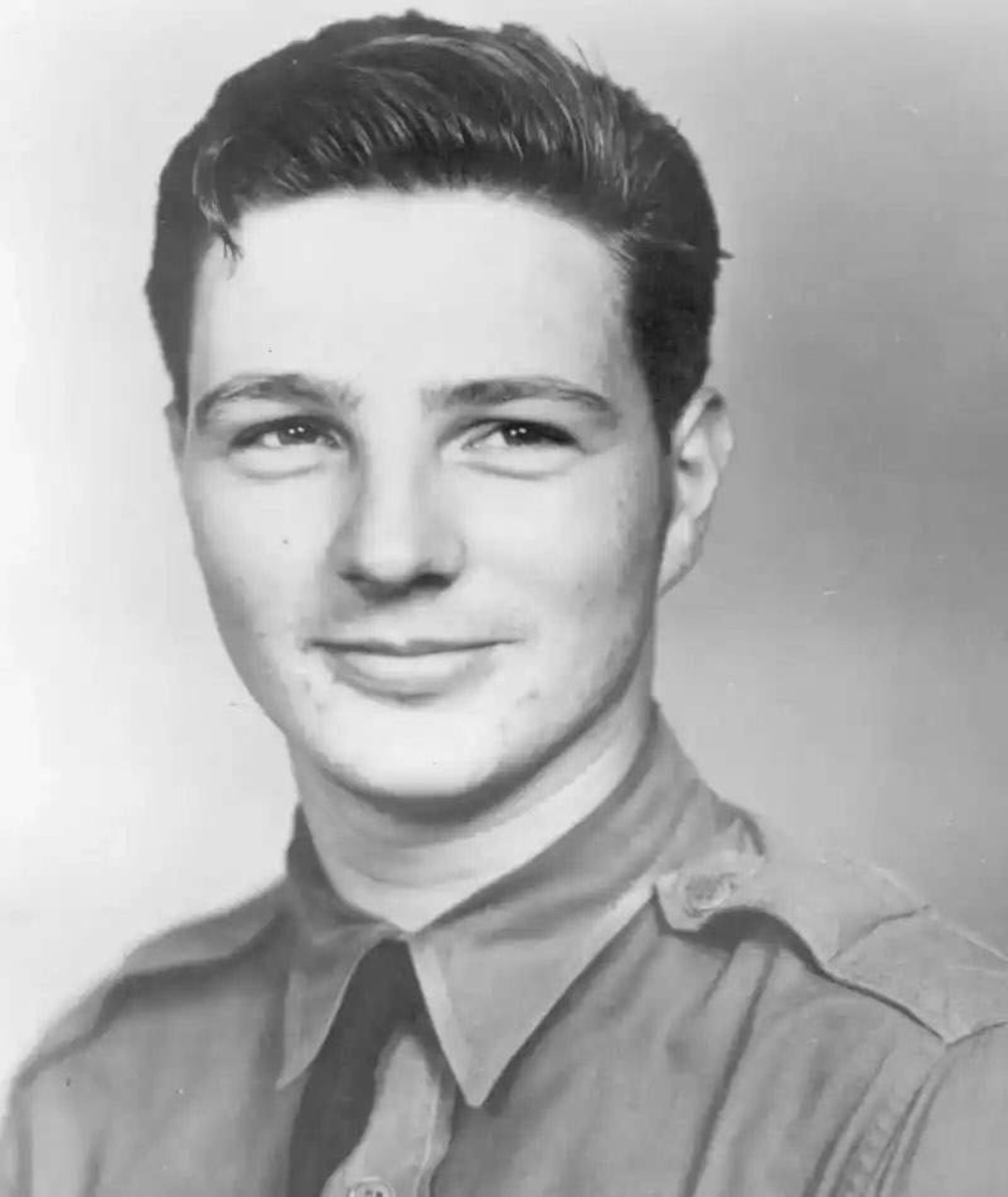 A black and white photo of a man posing for a photo while wearing a military uniform.