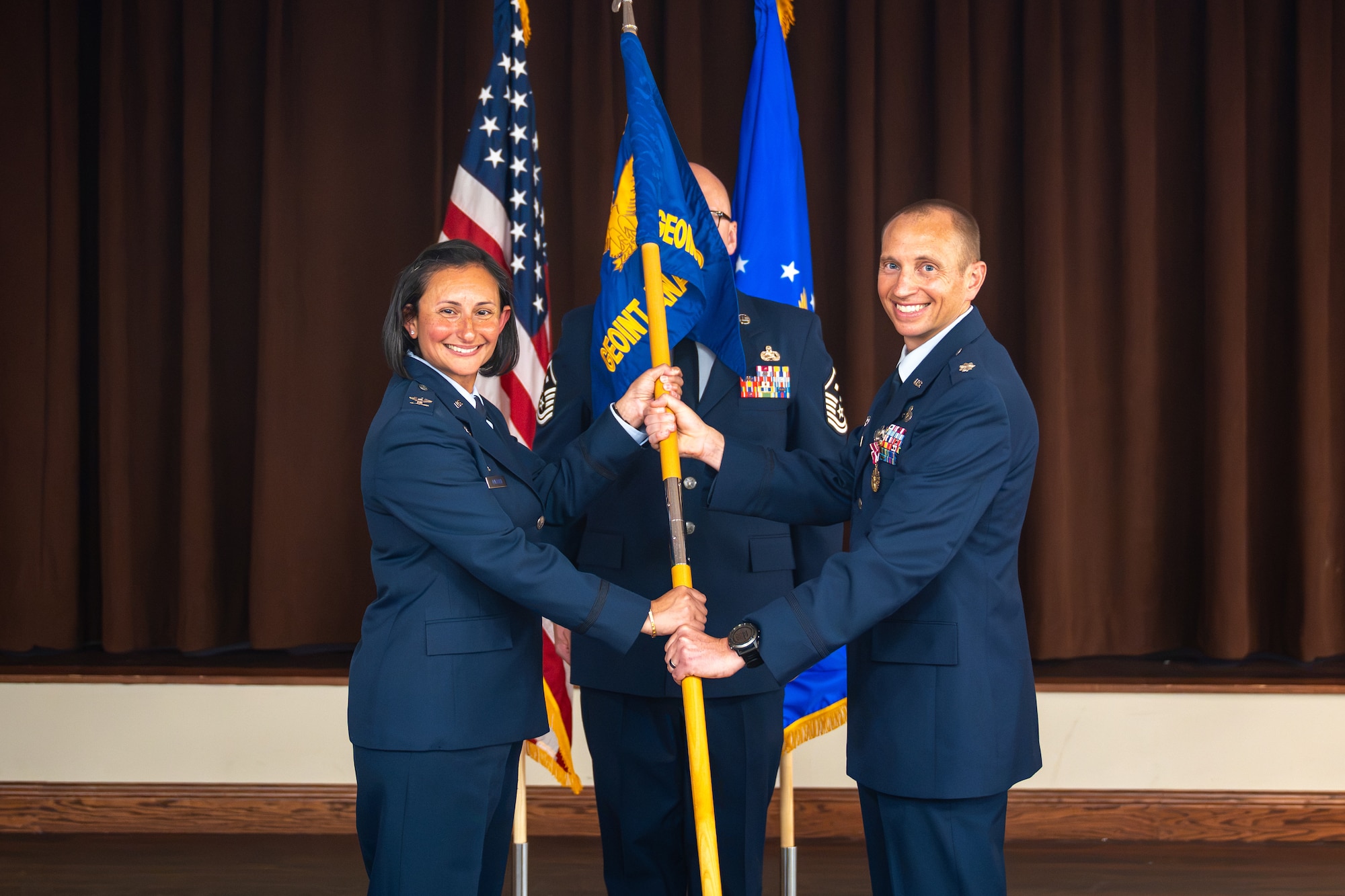 Lt. Col. Robert Vogt, right, outgoing Geospatial Intelligence Analysis Squadron commander, relinquishes the unit’s guidon to Col. Zarine E. Malesra, Geospatial and Signatures Intelligence Group commander, during a change of command ceremony at Wright-Patterson Air Force Base, Ohio, July 1, 2026. The passing of the guidon is a historic military tradition that represents the formal transfer of authority and responsibility from one commander to another. (U.S. Air Force photo by Staff Sgt. Kristof J. Rixmann)