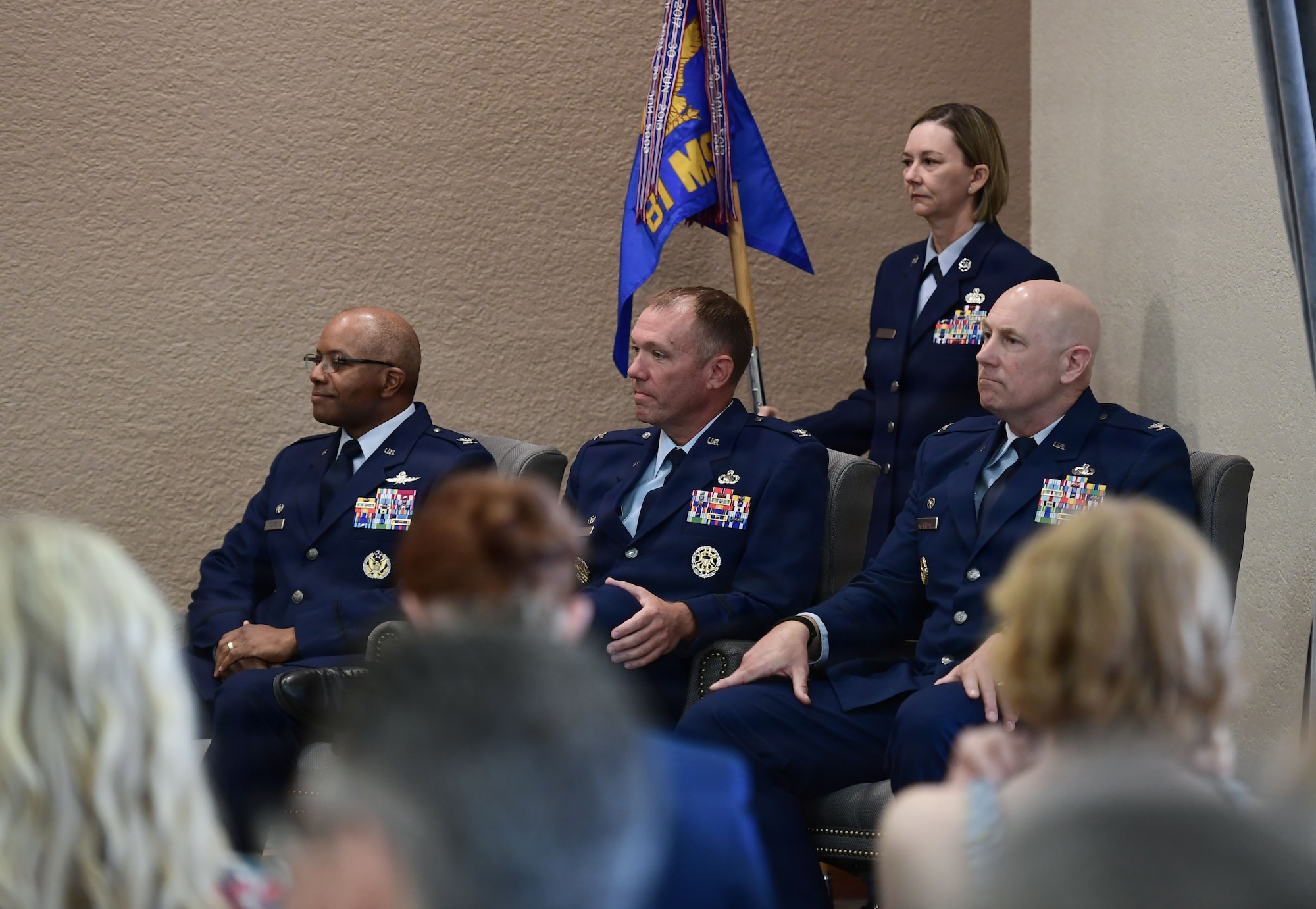 A group of people in U.S. Air Force uniforms sit on a stage.