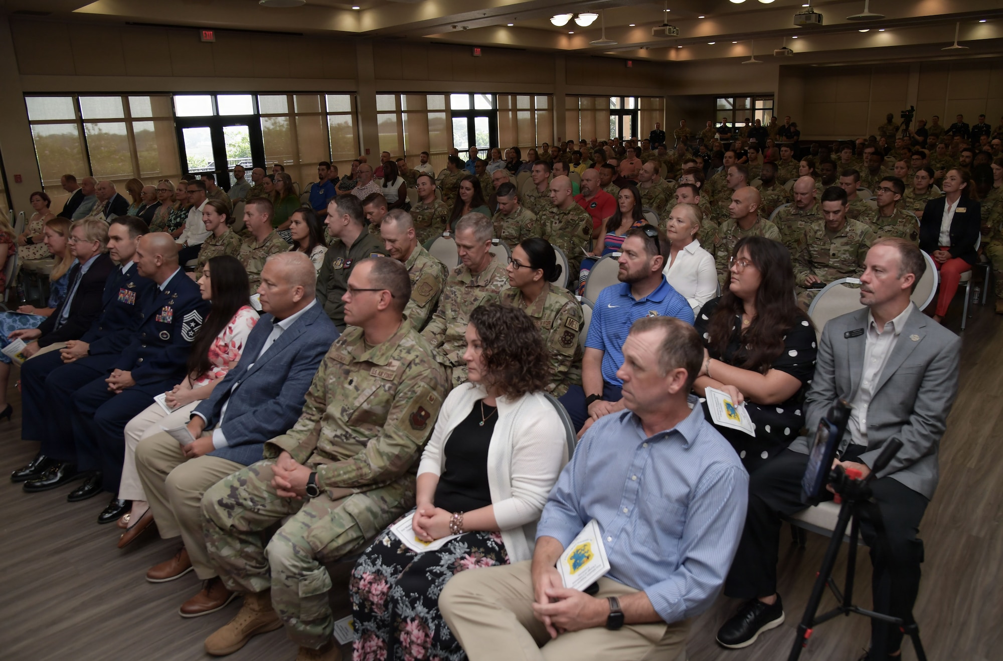A crowd of people sit on chairs in an audience.