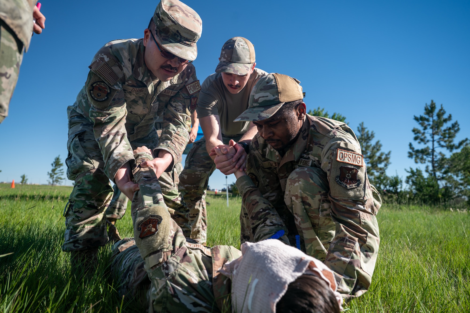 Military personnel practice Tactical Combat Casualty Care procedures on a simulated casualty during training.