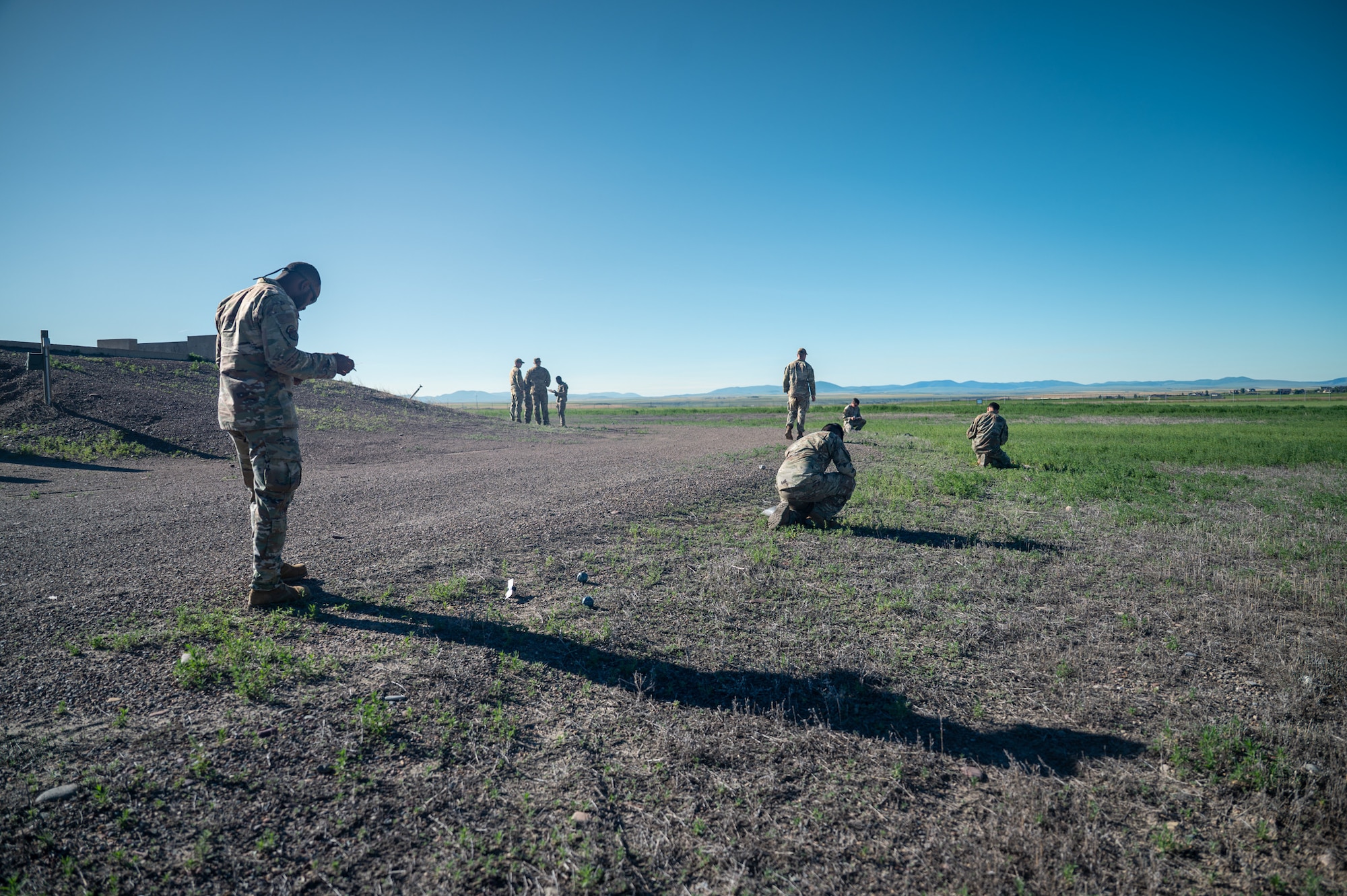 Military personnel spread across an area write notes in notepads.
