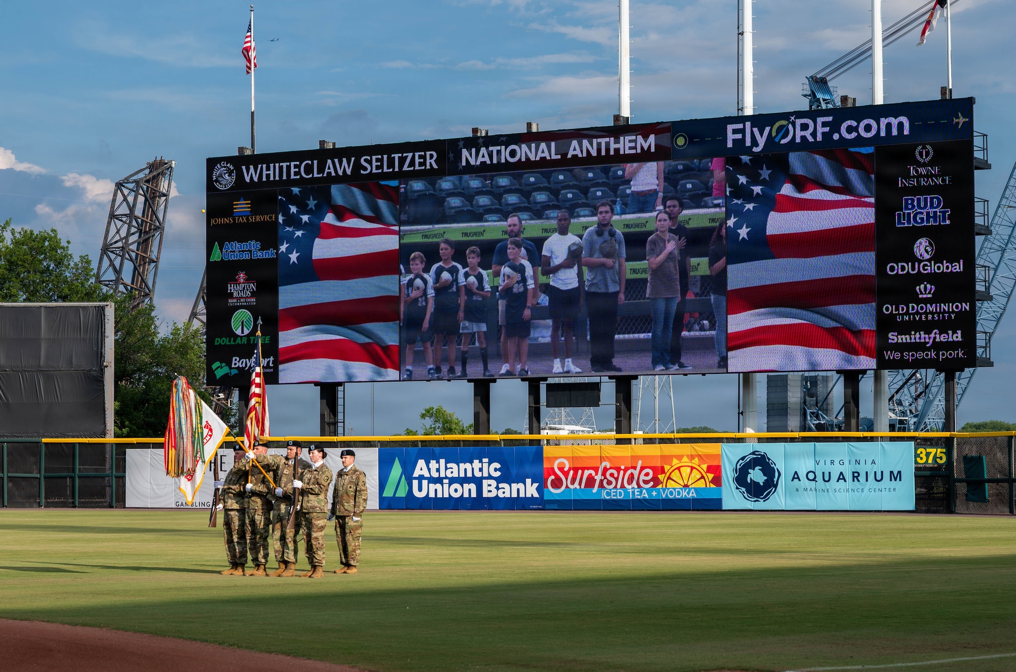 A group of Soldiers holds flags at a baseball field.