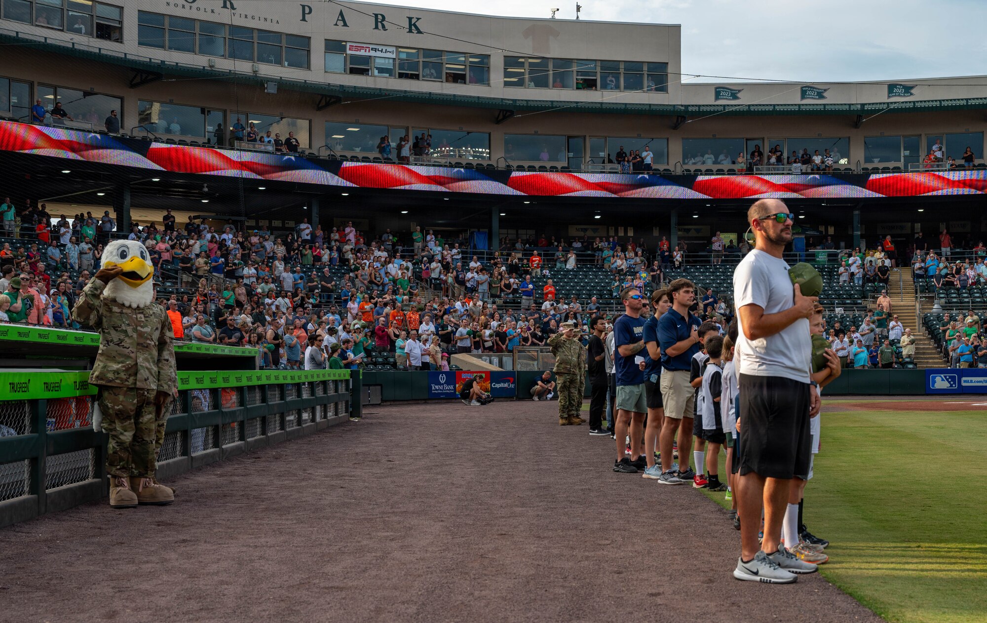 An eagle mascot and group of people stand in a baseball field.