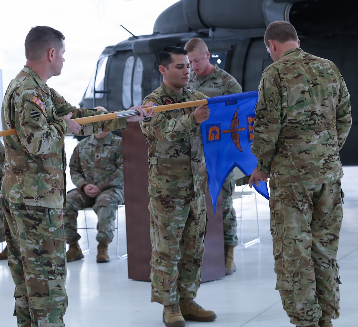Staff Sgt. Daniel Davis, the custodian of the colors of Detachment 2, Company G, 1-111th General Support Aviation Battalion, lowers the unit's guidon, allowing Capt. Jonathan Mercado, commander, and Sgt. 1st Class Timothy Panatera, detachment noncommissioned officer in charge, to case it. The 'casing' signifies the retiring of the MEDEVAC's colors.