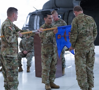 Staff Sgt. Daniel Davis, the custodian of the colors of Detachment 2, Company G, 1-111th General Support Aviation Battalion, lowers the unit's guidon, allowing Capt. Jonathan Mercado, commander, and Sgt. 1st Class Timothy Panatera, detachment noncommissioned officer in charge, to case it. The 'casing' signifies the retiring of the MEDEVAC's colors.