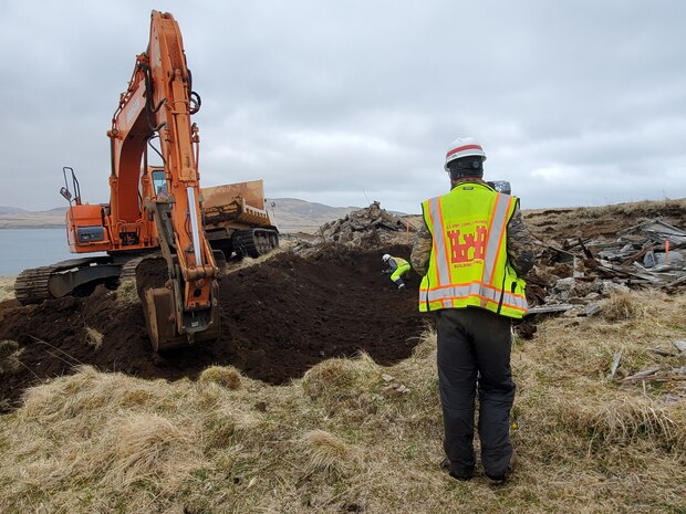 A man and an excavator meet on opposite sides of a hole. The situation is tense.