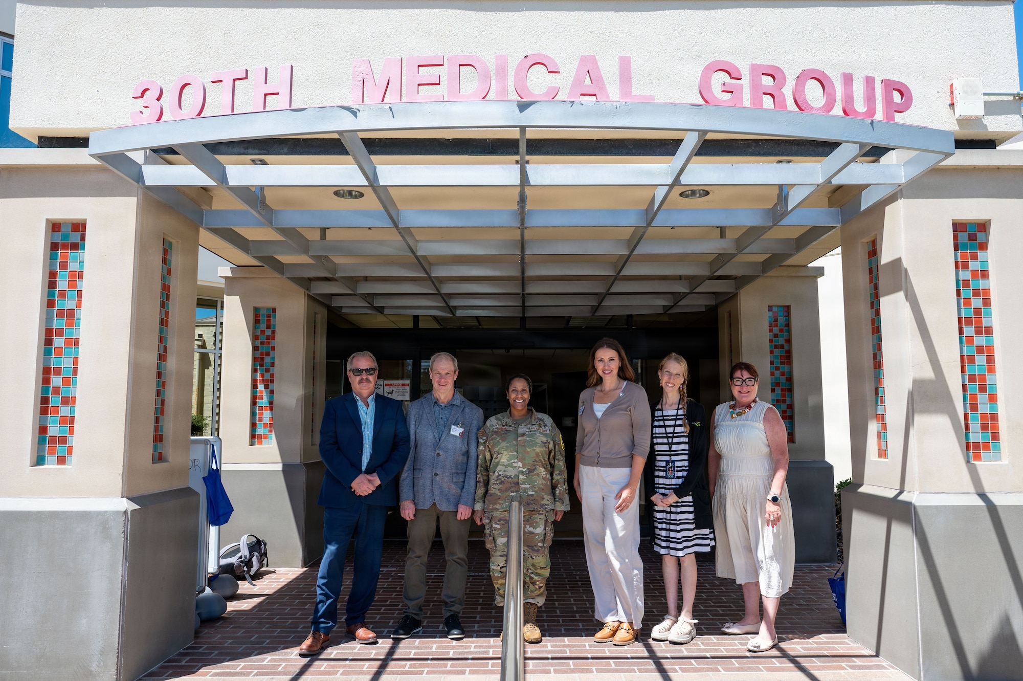 a group of people stand in a group under a sign that reads 30th medical group