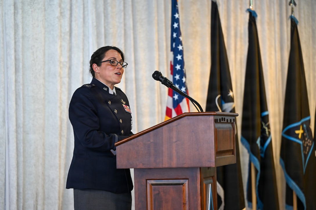 Woman addresses audience from podium in uniform