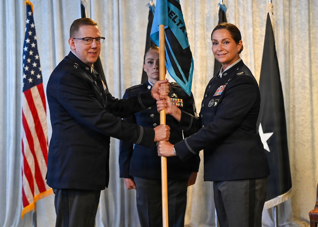 Man on left passing guidon to woman on right