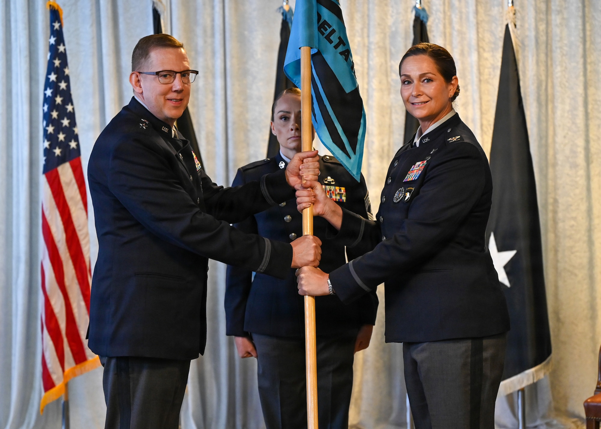Man on left passing guidon to woman on right