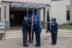 Four people stand. Two of the people hold a flag.