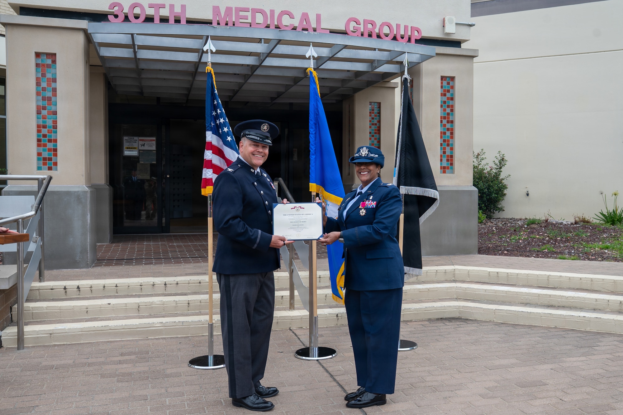 Two people stand and hold a certificate