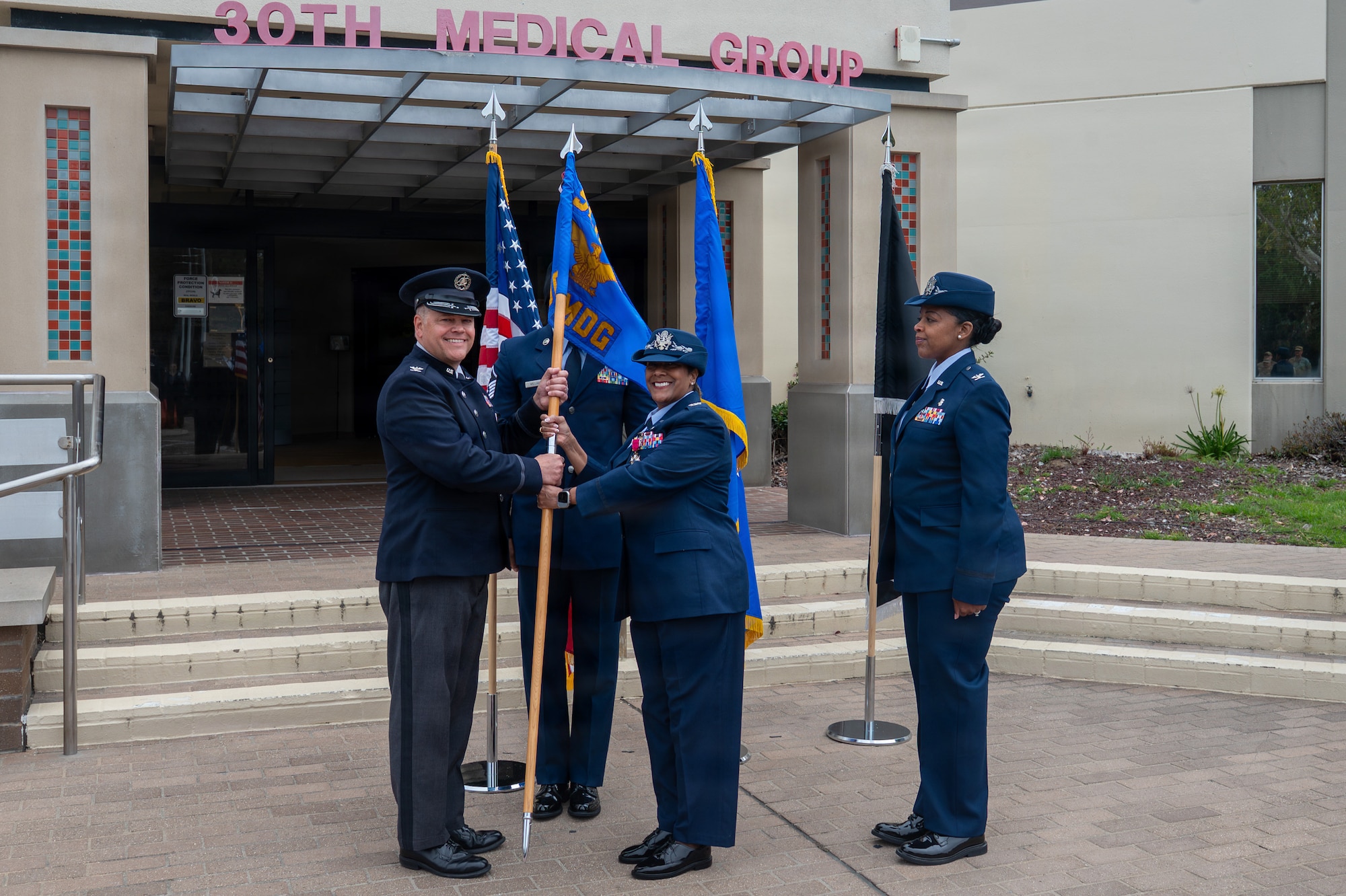 Four people stand. Two of the people hold a flag.