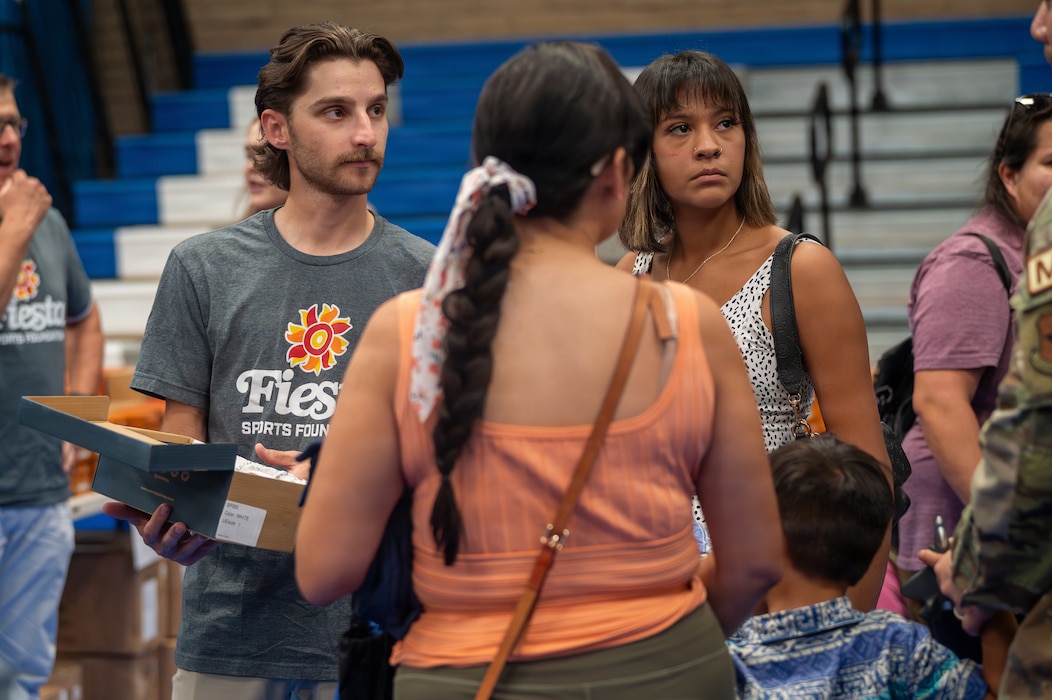 A volunteer helps a military family pick a pair of shoes during the Back to School Bash held at Luke Air Force Base, Arizona, July 14, 2026.