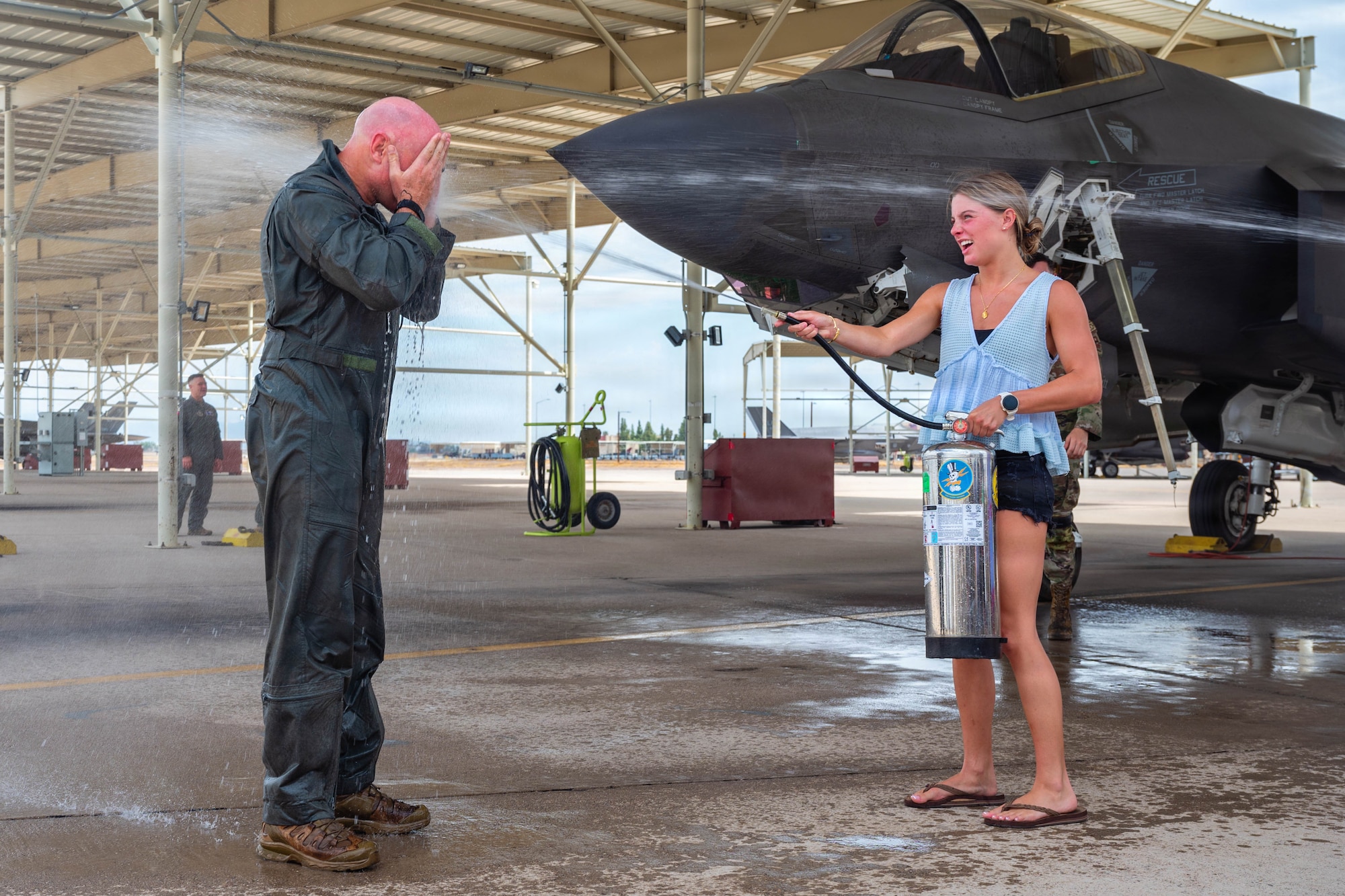 A U.S. Airman gets sprayed with water during a fini flight celebration.
