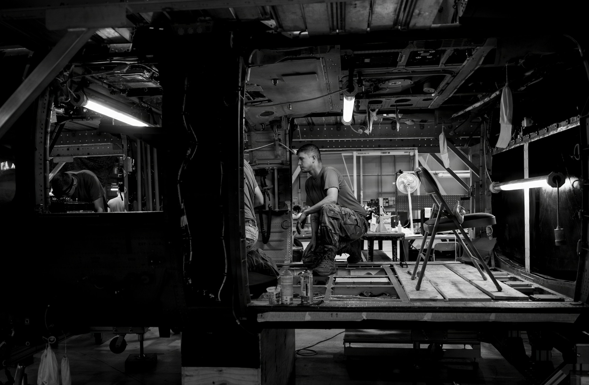 A group of men work on the inside of a helicopter.