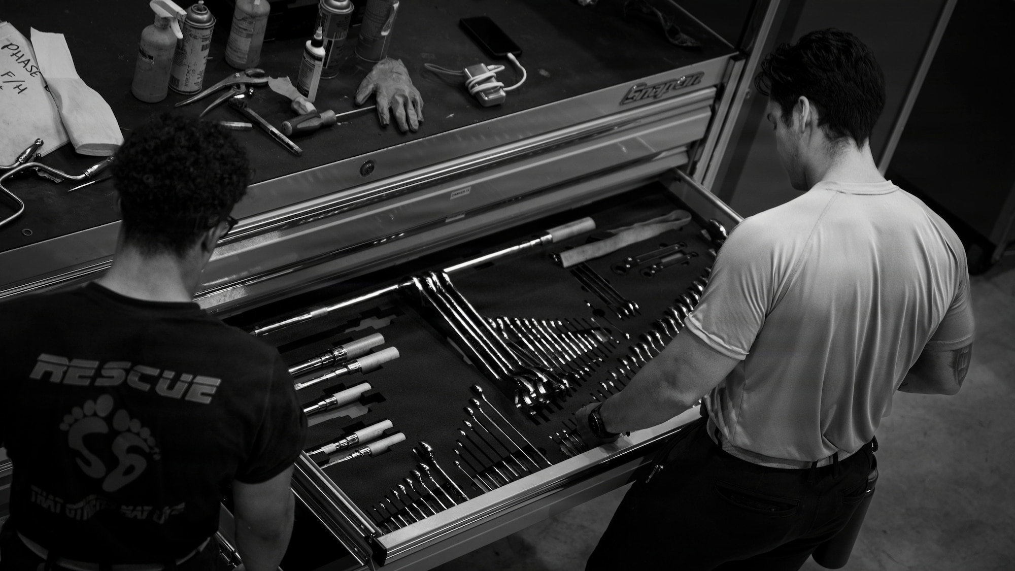 Two men take tools from a tool chest.
