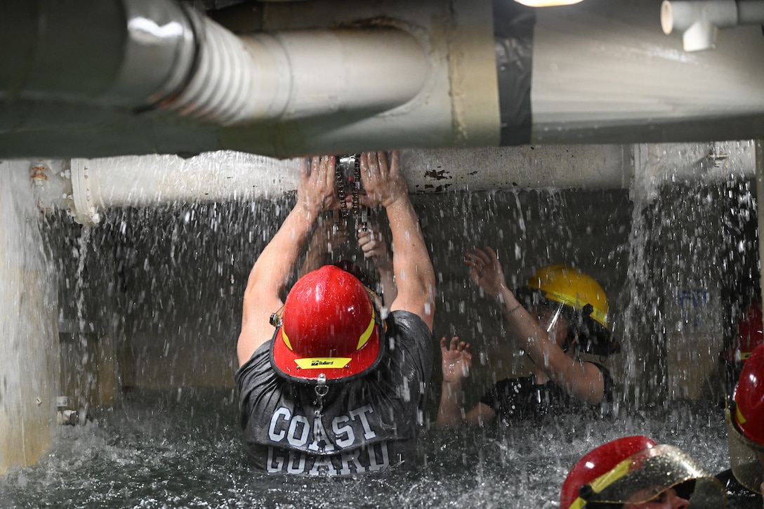 U.S. Coast Guard and Norwegian crew members participate in damage control training aboard the USS Buttercup wet trainer, July 13, 2026. The trainer simulates flooding and battle damage aboard a ship, allowing crews to practice emergency repair and damage control response. (U.S. Coast Guard photo by Petty Officer 2nd Class Laticia Sims)