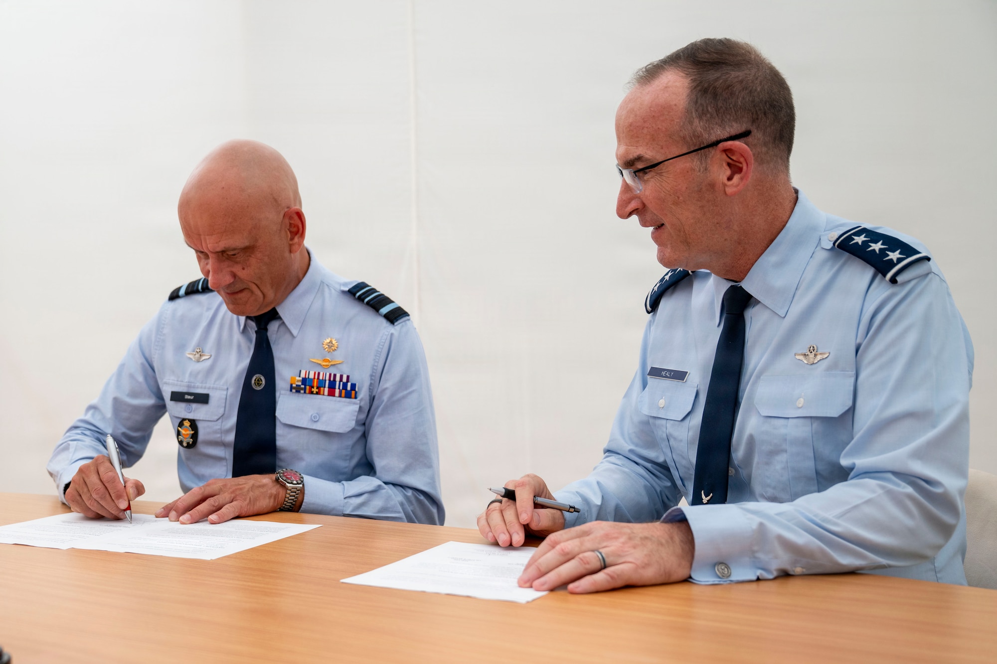 Two service members signing documents at a table