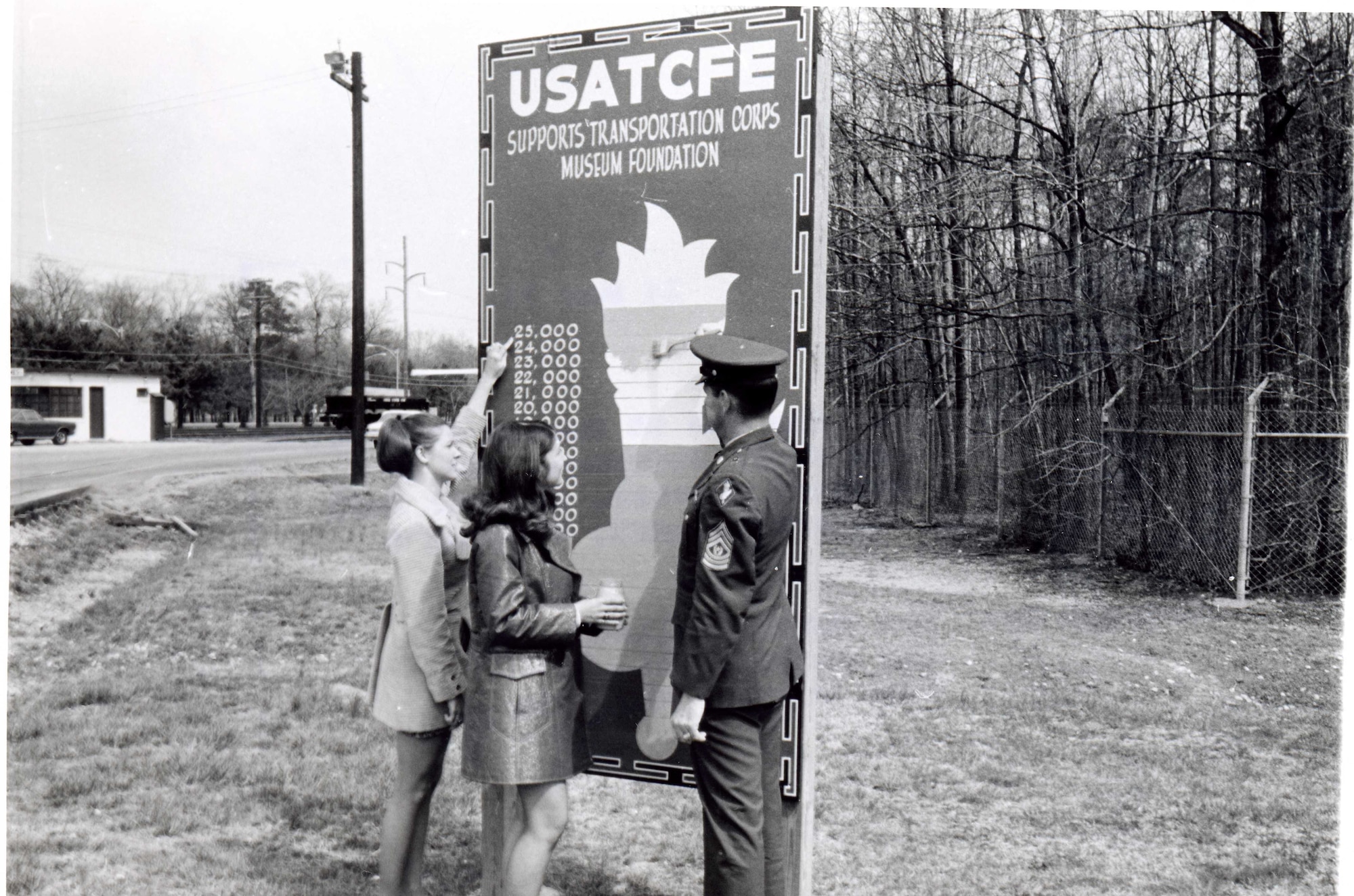 Mrs. Sprouse and Mrs. Leonard assist Transportation School Command Sergeant Major Jeffress updated the Transportation Museum fundraising board by the Fort Eustis gate in 1971. (Courtesy photo from U.S. Army Transportation Museum Photo Collection)