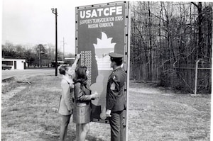 Mrs. Sprouse and Mrs. Leonard assist Transportation School Command Sergeant Major Jeffress updated the Transportation Museum fundraising board by the Fort Eustis gate in 1971. (Courtesy photo from U.S. Army Transportation Museum Photo Collection)