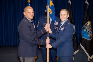 U.S. Air Force Col. Marcie Lewis, incoming 21st Medical Group commander, accepts the guidon from U.S. Space Force Col. Kenneth Klock, Space Base Delta 1 commander