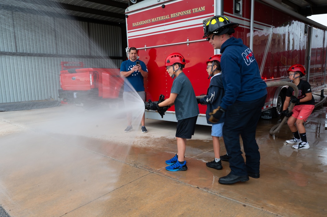 Goodfellow firefighters assist junior firefighters in operating a hose during a fire hose exercise during Junior Firefighter Camp, Goodfellow Air Force Base, Texas, July 16, 2026.