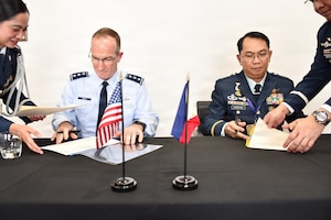 Two military members sign documents