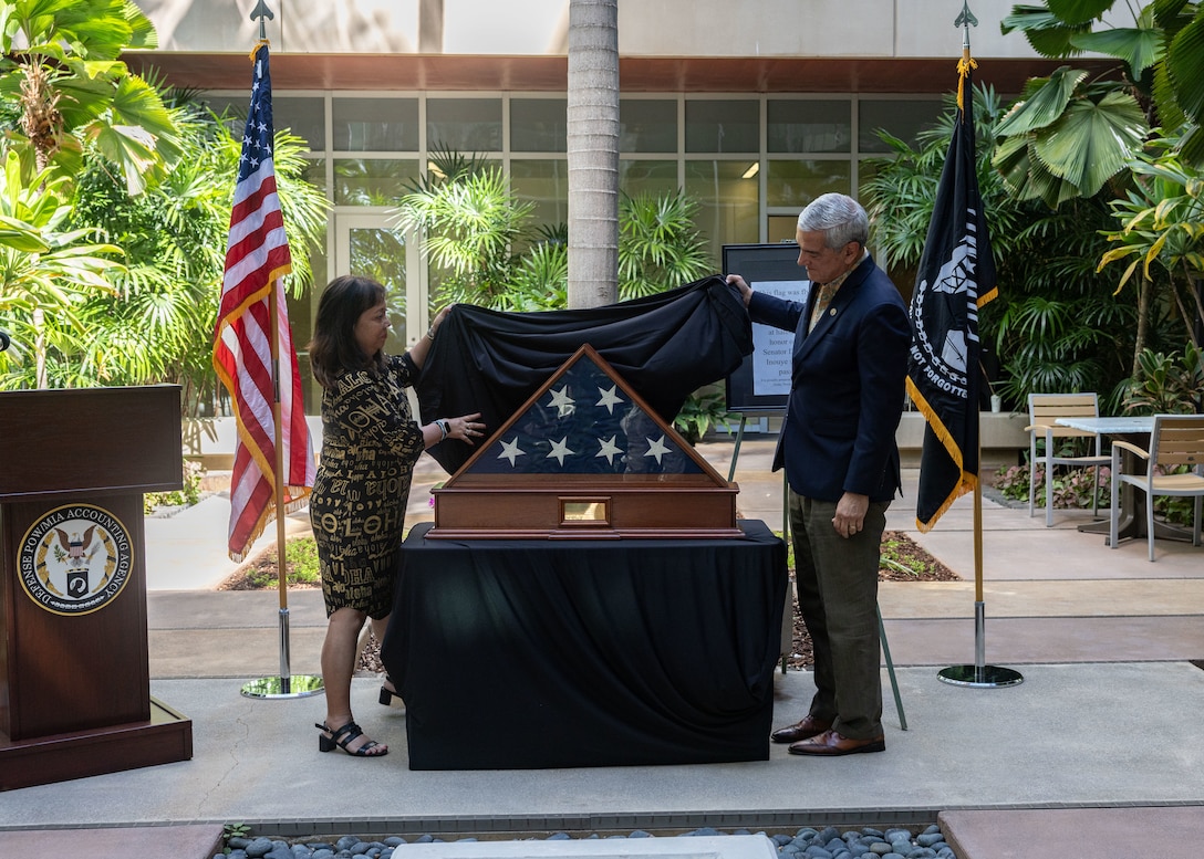 Kelly McKeague, Defense POW/MIA Accounting Agency director, and Jennifer Sabas, Director of the Daniel K. Inouye Institute, unveil the flag during a flag presentation ceremony at Joint Base Pearl Harbor-Hickam, Hawaii, July 17, 2026.