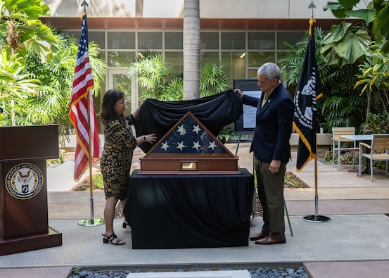 Kelly McKeague, Defense POW/MIA Accounting Agency director, and Jennifer Sabas, Director of the Daniel K. Inouye Institute, unveil the flag during a flag presentation ceremony at Joint Base Pearl Harbor-Hickam, Hawaii, July 17, 2026.