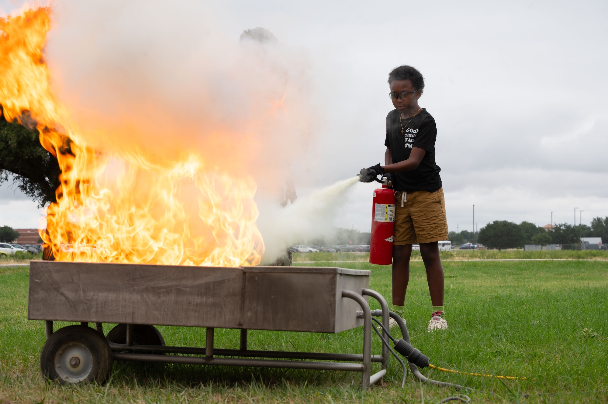 Neo Barton, junior firefighter, puts out a propane fire with a fire extinguisher during Junior Firefighter Camp, Goodfellow Air Force Base, Texas, July 15, 2026.