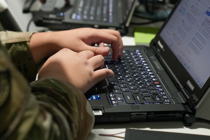 an Airman's hands type on a laptop