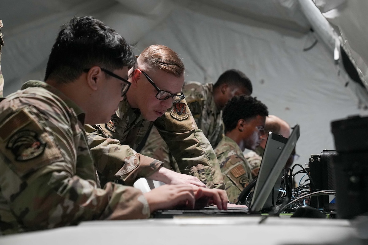 two airmen look at a laptop