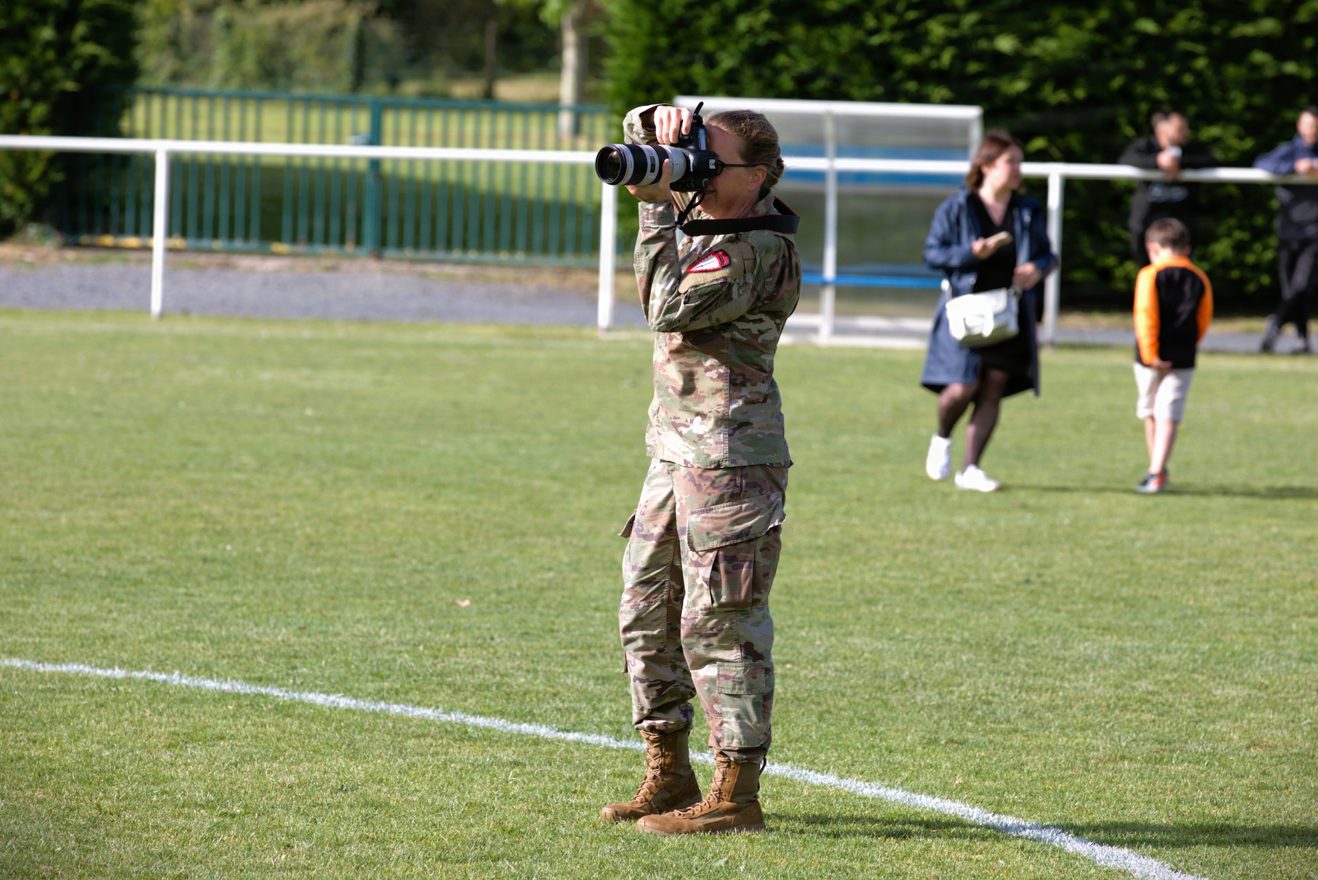 U.S. Army 1st Sgt. HollyAnn Nicom, senior enlisted leader of the 109th Mobile Public Affairs Detachment, U.S. Special Operations Command Europe, takes a photo during a soccer tournament in Saint-Hilaire-Petitville, France, June 4, 2026. The tournament featured a team of U.S. Soldiers with the 173rd Airborne Brigade, soldiers with the Franco-German Brigade, and coaches from a local Saint-Hilaire club. Friendly athletic events are one way U.S. service members who are taking part in D-Day 82 commemorations can connect on a personal level with the French community and continue to build on the foundation of shared values and vision going back 250 years. From June 2-7, 2026, more than 600 U.S. Soldiers, Sailors, Marines, Guardians and Airmen from roughly 17 units historically linked to D-Day made up Joint Task Force 82 and participated in over 90 commemorative events throughout the Normandy Region. (U.S. Army National Guard photo by Maj. Travis Mueller)