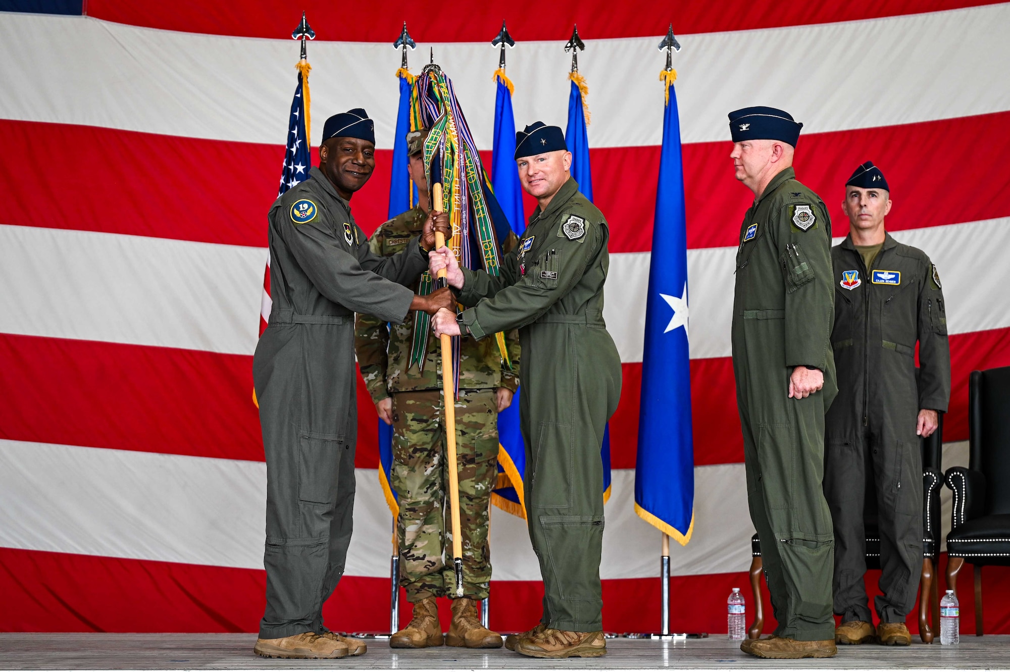 U.S. Air Force Brig. Gen. Travolis Simmons, 19th Air Force commander, left, receives the 56th Fighter Wing guidon from Brig. Gen. David Berkland, outgoing 56th FW commander, during a change of command and major command reassignment ceremony at Luke Air Force Base, Arizona, July 17, 2026.