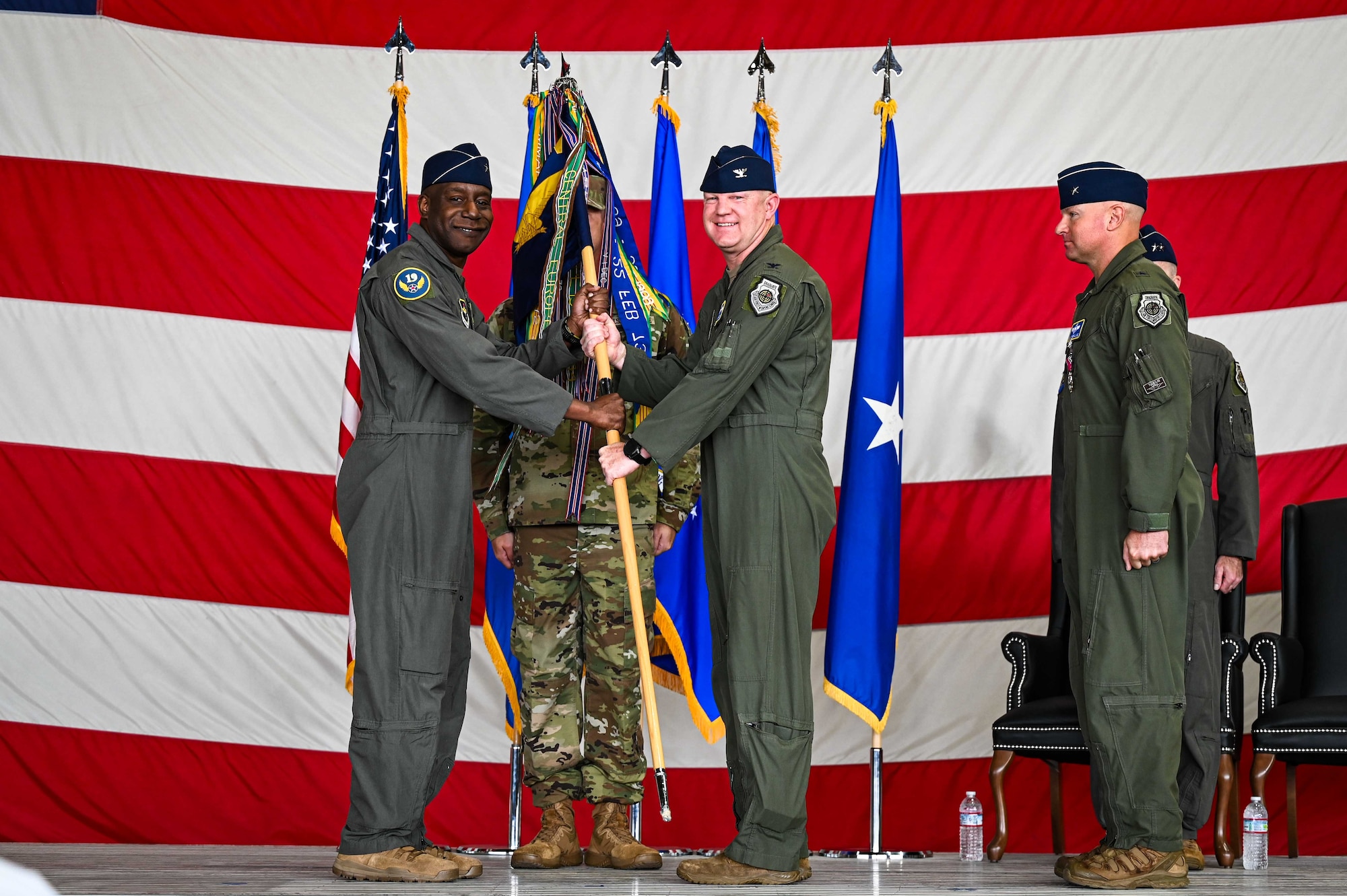 U.S. Air Force Brig. Gen. Travolis Simmons, 19th Air Force commander, left, passes the 56th Fighter Wing guidon to Col. Nicholas Ihde, incoming 56th FW commander, during a change of command and major command reassignment ceremony at Luke Air Force Base, Arizona, July 17, 2026.