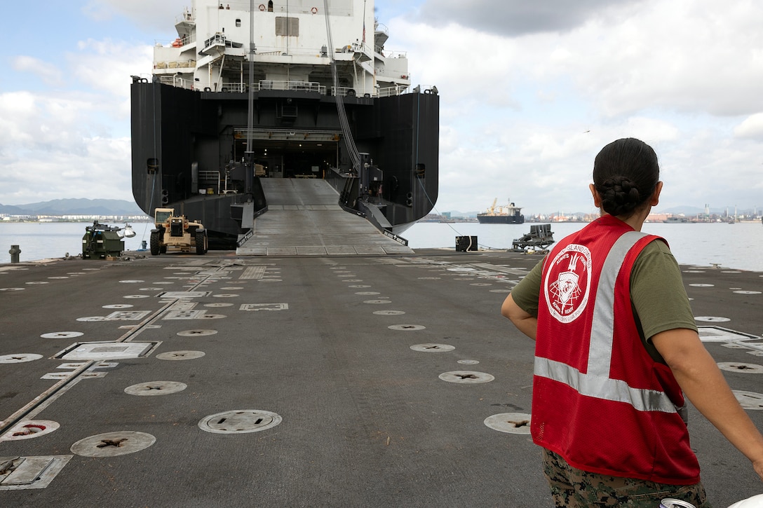 U.S. Marine Corps Sgt. Mariah Aparicio, an embarker assigned to Blount Island Command's technical assistance and advisory team, oversees offload operations July 14, 2026, from a roll-on, roll-off discharge facility connected to the stern ramp of USNS Sisler near Pohang, South Korea. Blount Island Command personnel supported embarkation, equipment accountability and maritime sustainment during Combined Joint Logistics Over-the-Shore 26, which integrated U.S. and Republic of Korea lighterage and ship-to-shore connector capabilities. (U.S. Marine Corps photo by Dustin Senger)