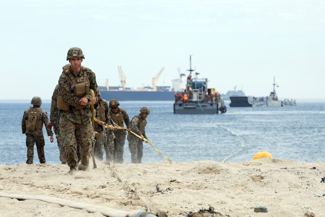 U.S. Marines assigned to 9th Engineer Support Battalion, 3rd Marine Logistics Group, pull a fuel line ashore from an Improved Navy Lighterage System causeway ferry during a capabilities demonstration July 16, 2026, at Dogu Beach, Pohang, South Korea, as part of Combined Joint Logistics Over-the-Shore 26. The event demonstrated expeditionary bulk fuel distribution capabilities using forward-positioned, service-managed equipment as U.S. and Republic of Korea forces integrated lighterage and ship-to-shore connector capabilities. (U.S. Marine Corps photo by Dustin Senger)