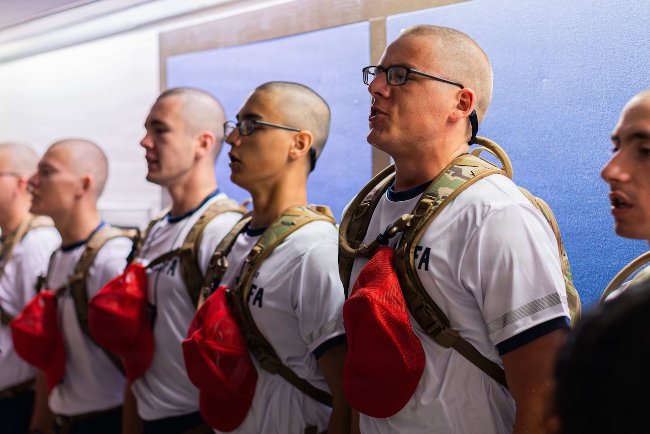 Six men wearing military physical training gear stand in formation.
