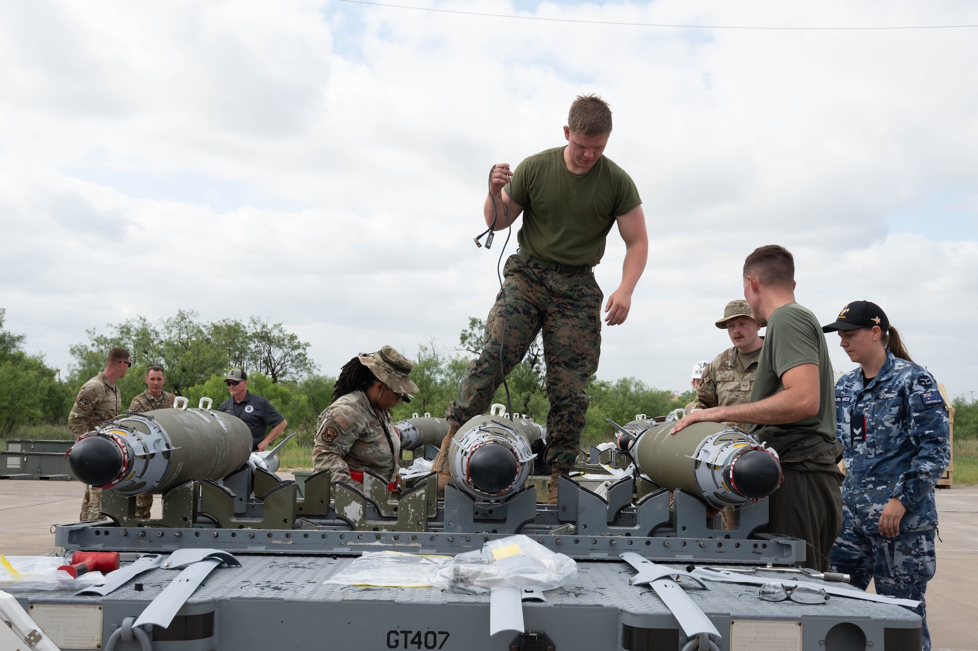 U.S. Air Force, U.S. Marine and Royal Australian Air Force service members work together to build conventional munitions during the Death Strike: Trident Fury exercise at Dyess Air Force Base, Texas, June 24, 2026. Death Strike: Trident Fury is a multi-day munitions production exercise focused on strengthening interoperability and proving the joint force's ability to rapidly scale operations in a simulated combat environment. (U.S. Air Force photo by Airman 1st Class William Neal) This photo was altered for security purposes by blurring out nametapes.