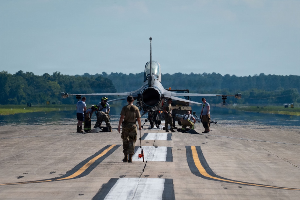 Airmen surround a fighter aircraft on a runway