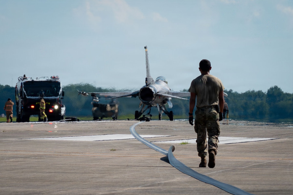 An Airman walks towards a fighter jet