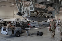 U.S. Airmen assigned to the 7th Munitions Squadron guide a Joint Air-to-Surface Standoff Missile into a Launcher Load Frame during a Multi-Role Pylon Load training event as part of the Death Strike: Trident Fury exercise at Dyess Air Force Base, Texas, June 22, 2026. The backshop training evaluated the crews' ability to rapidly configure and load heavy weapons directly onto launcher load frames within the facility. (U.S. Air Force photo by Airman 1st Class William Neal)